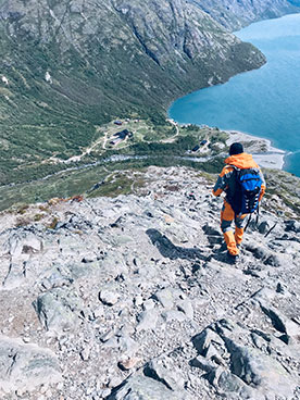 Person vandrer på højt bjerg med udsigt over vandet