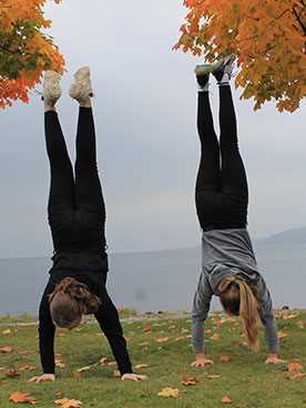 To piger står på hænder på en bjergtop